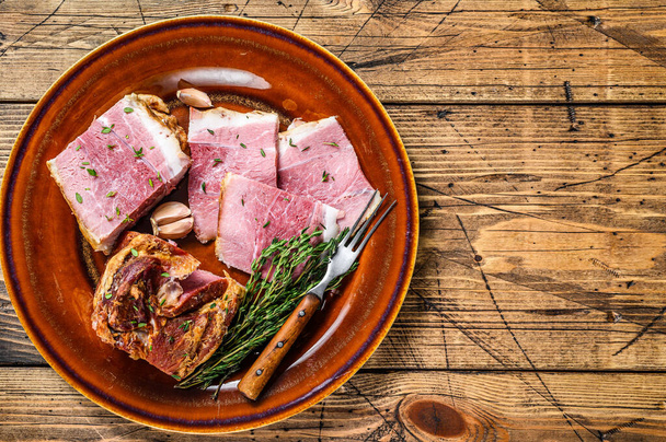 Losa de cerdo ahumada Rebanadas de carne de tocino en un plato rústico. fondo de madera. Vista superior. Copiar espacio - Foto, imagen