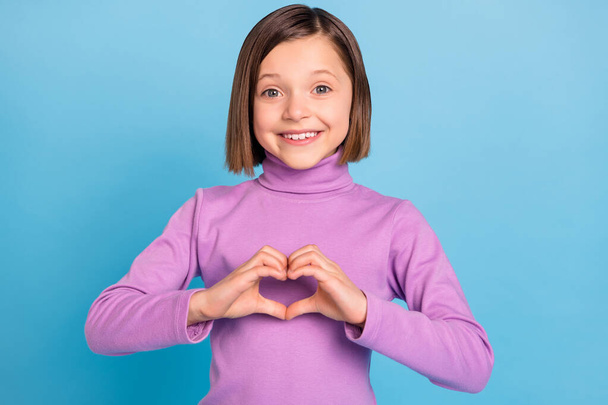 Photo portrait schoolgirl showing heart sign smiling isolated pastel blue color background - Foto, afbeelding