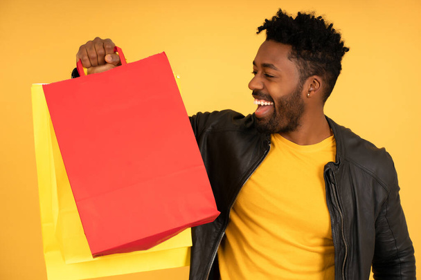Afro férfi mosolyog, miközben a kezében bevásárlótáskák. - Fotó, kép