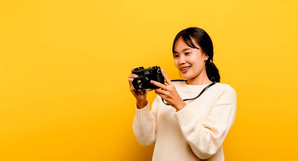 beautiful young asian tourist Studio shot with camera in hand isolated on yellow background. photography concept - Foto, Bild
