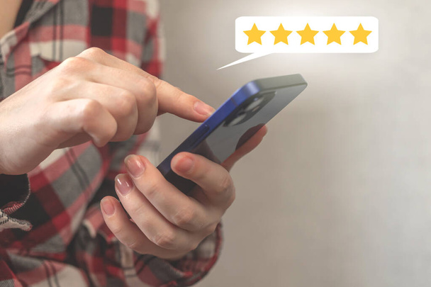 Cliente premendo sullo schermo dello smartphone con oro cinque stelle o icona di feedback, rango eccellente o miglior punteggio per il servizio, business concept background - Foto, immagini