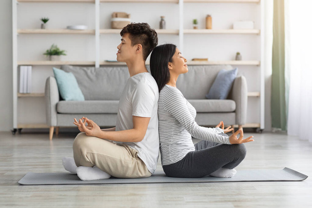 Asiatische Mann und Frau sitzen Rücken an Rücken und meditieren - Foto, Bild