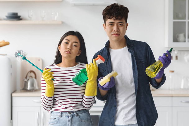 Bored asian man and woman holding cleaning tools - Photo, Image