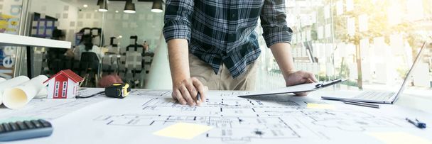 Interior designer or architect reviewing blueprints and holding pencil drawing on desk at home office. - Foto, immagini