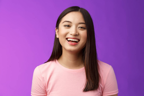 Close-up lively carefree cheerful asian girl laughing, having fun, smiling amused enjoy friendly relaxing conversation, stand purple backgrond joyful, look camera upbeat - Foto, Imagen