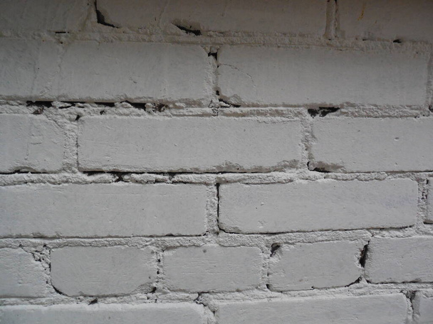 A wall with old crumbling brickwork, painted with white paint. - Fotoğraf, Görsel