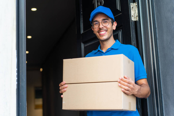 Young delivery man at outdoors holding boxes with happy expression - Foto, Imagen