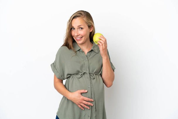 Молодая белая женщина изолирована на белом фоне беременной и держит яблоко - Фото, изображение