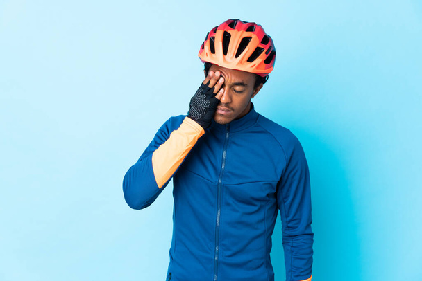 Mladý cyklista muž s copánky přes izolované pozadí s bolestí hlavy - Fotografie, Obrázek