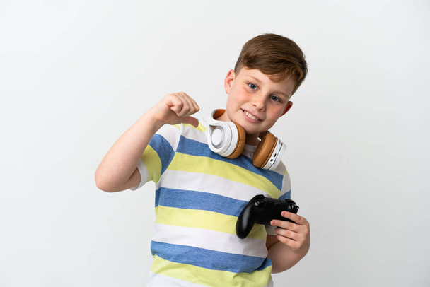 Malý ryšavý chlapec drží herní podložku izolované na bílém pozadí hrdý a self-spokojen - Fotografie, Obrázek