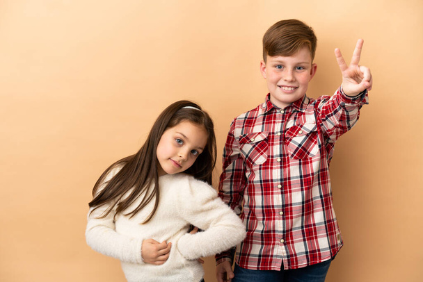Little caucasian brother and sister isolated on beige background - Foto, Imagen