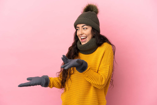 Young caucasian girl with winter hat isolated on purple background with surprise expression while looking side - Photo, Image