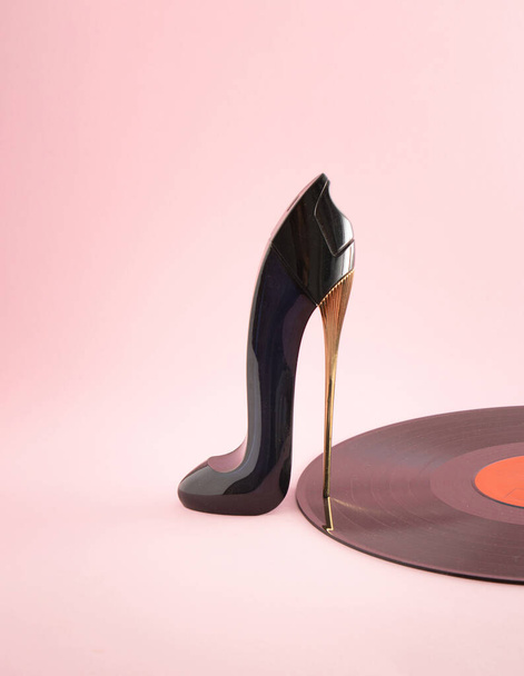 Dámská bota s vysokými podpatky a vinylem na pastelově růžovém pozadí. Minimální kreativní abstraktní nápad s výtvarným uměním. Koncept diskotéky Retro. - Fotografie, Obrázek