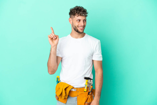 Young electrician blonde man isolated on green background intending to realizes the solution while lifting a finger up - Foto, Imagen