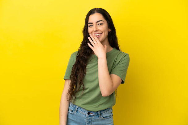 Young caucasian woman isolated on yellow background looking up while smiling - Photo, Image