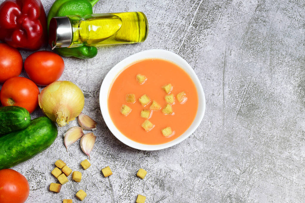 Andalusian homemade gazpacho, from Spain, served on a white plate with breads and exposed with its ingredients. Healthy and beneficial. Zenith view and copy space. - Photo, Image