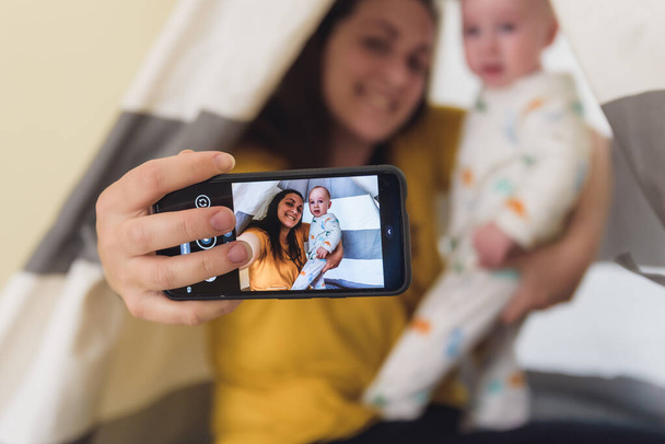 woman with her baby taking a picture while playing. family time - Foto, imagen