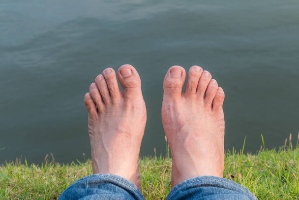 Descanse e relaxe os pés descalços na grama verde com fundo natural lago - Foto, Imagem