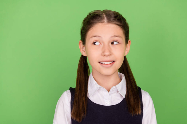 Photo of charming thoughtful schoolgirl wear formal outfit smiling looking empty space isolated green color background - Fotoğraf, Görsel