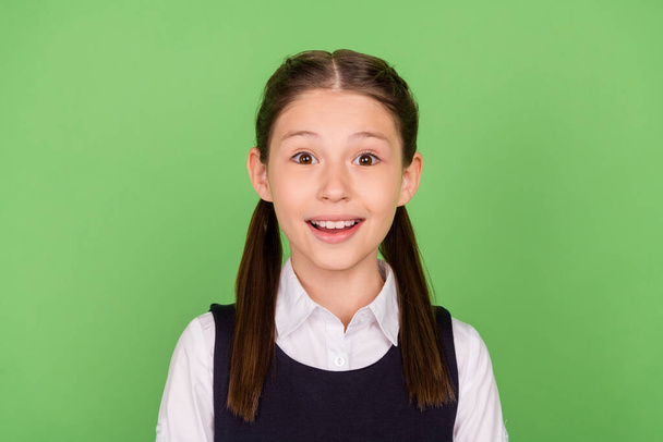 Photo of young school girl happy positive smile amazed surprised news isolated over green color background - Fotografie, Obrázek