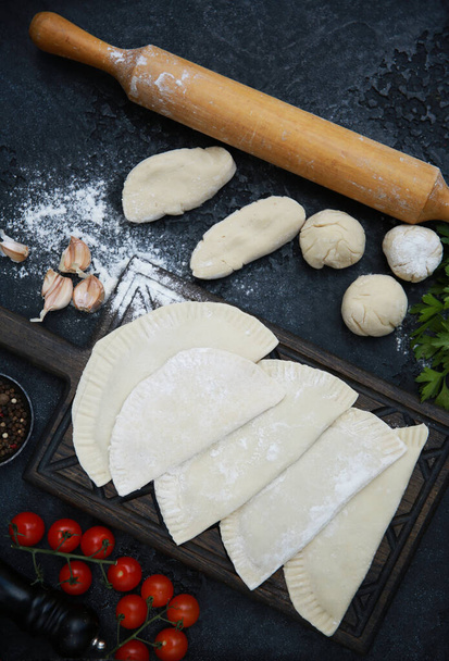The national dish is Tatar cuisine. Preparation. The culinary process of chebureks. Raw dough with minced meat, rolling pin, flour, herbs, tomatoes, spices and garlic. Background image, copy space - Fotoğraf, Görsel