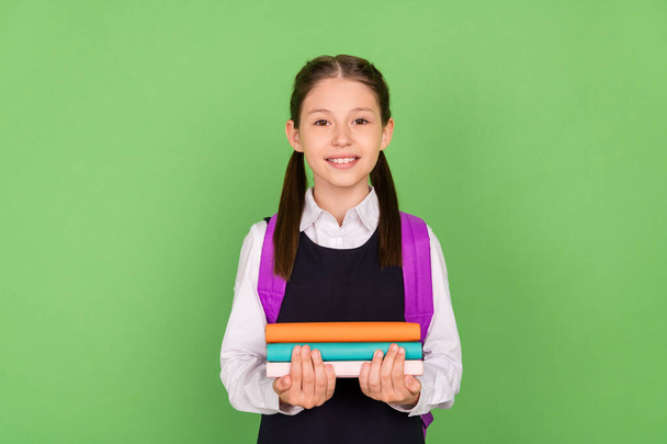 Photo of young school girl happy positive smile education study hold book learn isolated over green color background - Foto, immagini