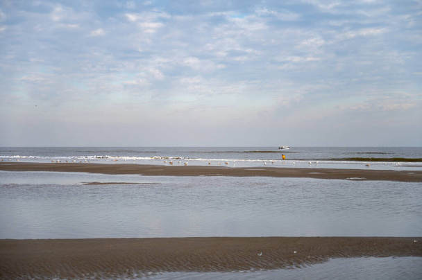 Période de balade à basse altitude sur une plage de sable jaune dans une petite ville belge De Haan ou Le Coq sur mer, destination de vacances de luxe, vacances d'été le jour ensoleillé - Photo, image