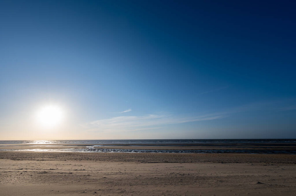 Κίτρινη αμμώδης παραλία στη μικρή βελγική πόλη De Haan ή Le Coq sur mer, προορισμός πολυτελών διακοπών, καλοκαιρινές διακοπές στο ηλιοβασίλεμα - Φωτογραφία, εικόνα