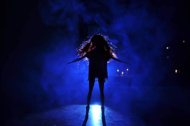 Силуэт женского лица на светлом фоне. Силуэт одинокого человека с длинными волосами по ночам синим светом на туманном фоне. Селективный фокус - Фото, изображение