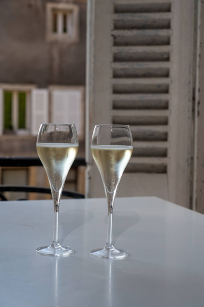 Romantický večírek se dvěma sklenicemi bílého studeného šampaňského šumivého vína s bublinkami a výhledem na starou ulici ve francouzské vesnici - Fotografie, Obrázek