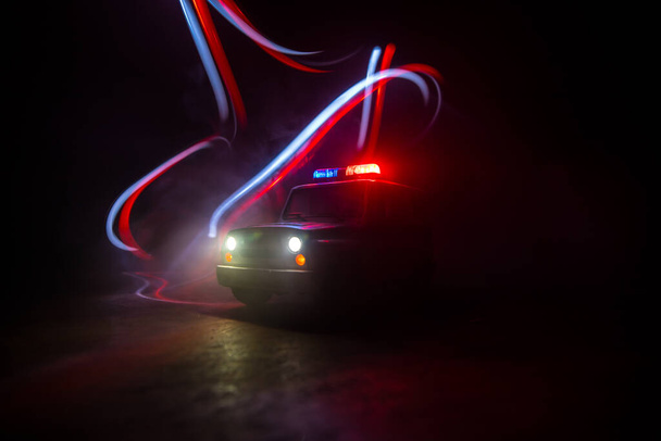 Coche de policía persiguiendo un coche por la noche con niebla de fondo. 911 Emergencia respuesta coche de policía exceso de velocidad a la escena del crimen. Decoración creativa. Enfoque selectivo - Foto, imagen