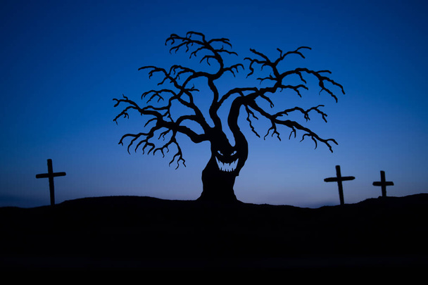 Силуэт некоторые зомби на кладбище ходить вокруг на закате. Силуэт пугающего Хэллоуинского дерева с жутким лицом. Ужасный Хэллоуин. Селективный фокус
 - Фото, изображение