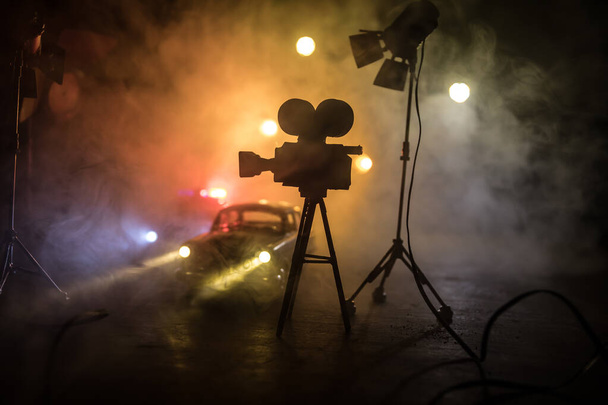 Actiefilm concept. Politieauto 's en miniatuurfilm op donkere achtergrond met mist. Politieauto die 's nachts een auto achtervolgt. Plaats van het misdrijf ongeluk. Selectieve focus - Foto, afbeelding