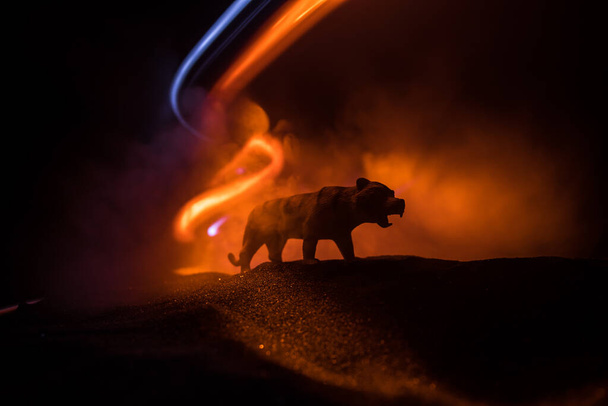 Silueta de un tigre en miniatura de pie en la noche brumosa. Decoración creativa con retroiluminación colorida con niebla. Enfoque selectivo - Foto, imagen