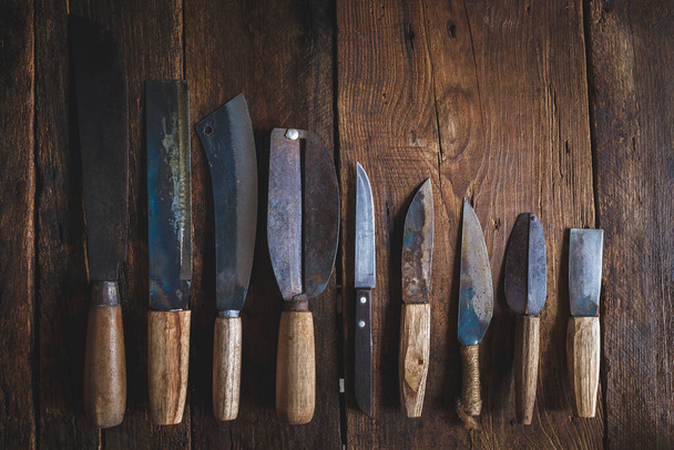 A top view of a set of knives with wooden handles on a wooden table - Фото, изображение