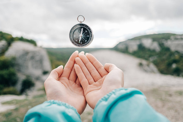 Compass hovers in levitation over female hands in the background nature. - Foto, immagini