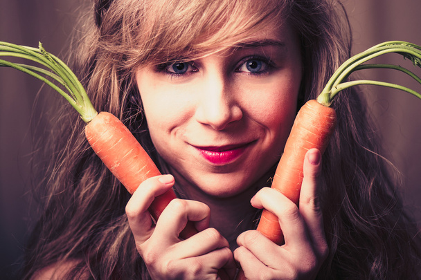 Brunette woman  with carrots - Фото, изображение