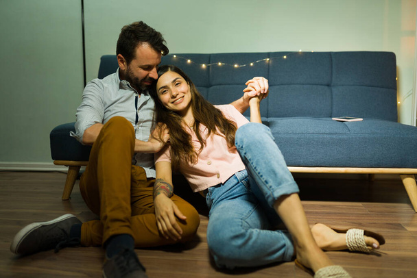 Siamo innamorati. Attraente giovane coppia che si abbraccia in soggiorno e si gode la loro nuova casa durante un appuntamento freddo  - Foto, immagini