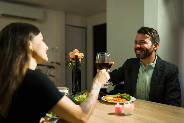 Brindiamo al nostro futuro. Bello marito e bella moglie fare un brindisi al loro amore con il vino durante un appuntamento cena fantasia - Foto, immagini