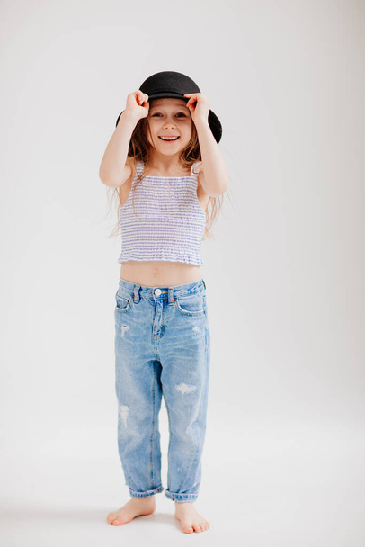 Cute little girl plays with a black hat. the child tries on mothers clothes. - Fotoğraf, Görsel