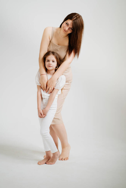 Mom and daughter pose in a white photo studio. - Foto, Imagen