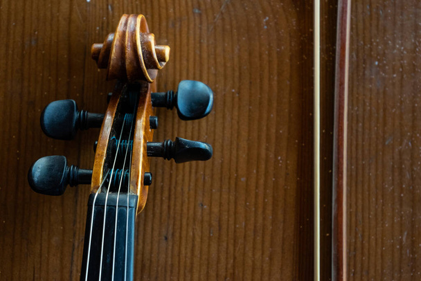Part of a violin on a brown background. Violin handle. Place for text - Photo, Image
