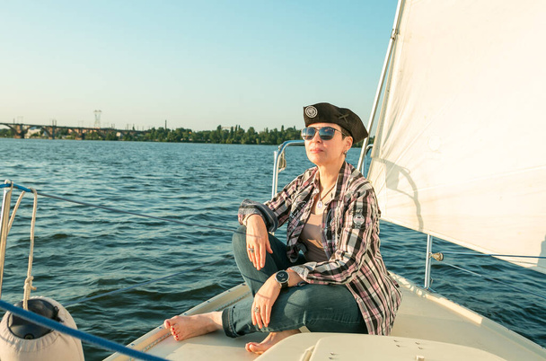 Роскошный отдых на яхте. Счастливая красивая женщина средних лет в солнечных очках на палубе лодки плавает по реке. - Фото, изображение