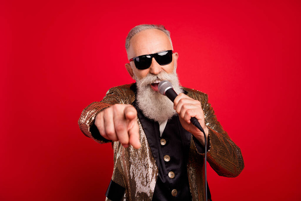 Photo of happy retired pensioner old man sing you mic good mood wear sunglass isolated on red color background - Fotoğraf, Görsel