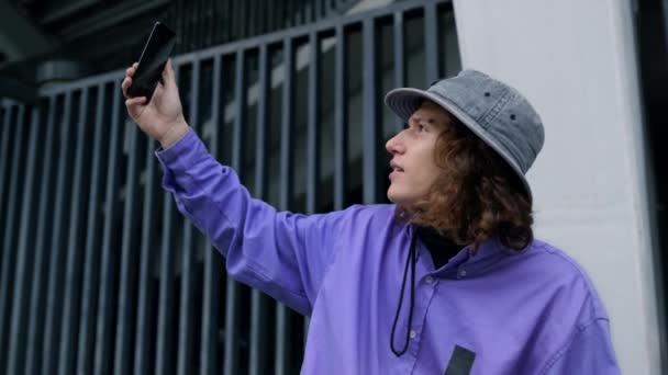 Komoly ember kezében okostelefon a szabadban. Hipster szelfit készít a kamerával.. - Felvétel, videó