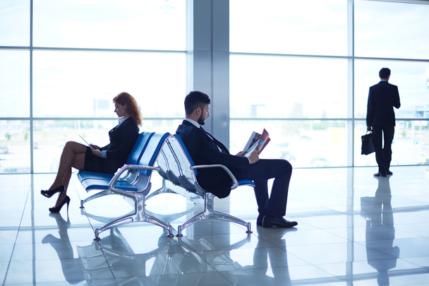 Business partners reading at the airport - Foto, imagen