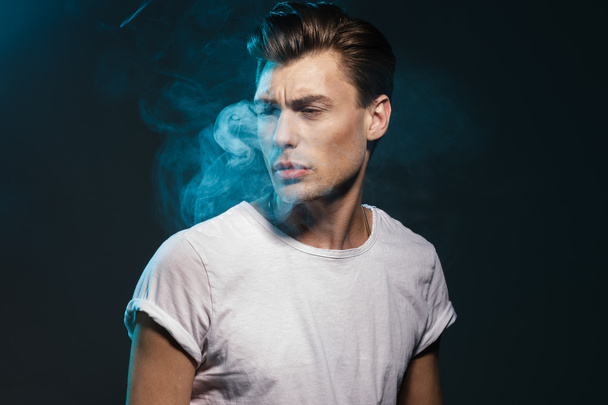 Handsome young man smoking cigarette - Foto, afbeelding