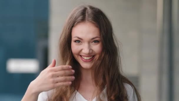 Female portrait outdoors beautiful friendly smiling seductive flirting millennial girl woman lady standing in city making invitation gesture with hand calling come up inviting welcome sign call here - Footage, Video
