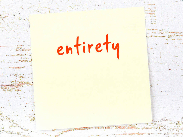 Concept of reminder about entirety. Yellow sticky sheet of paper on wooden wall with inscription - Photo, Image