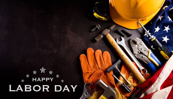 Happy Labor Day Konzept. Amerikanische Flagge mit verschiedenen Bauwerkzeugen mit dem Text auf dunklem Steinhintergrund. - Foto, Bild